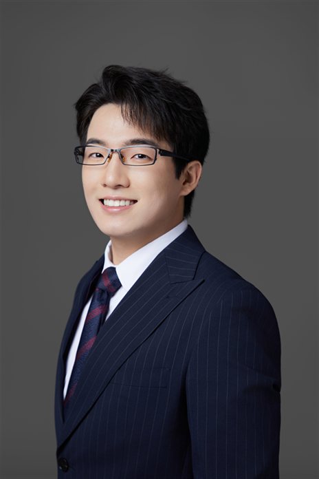 Liam Zhan, founder of Zhan Supply Co., in a navy pinstripe suit against a grey studio backdrop.
